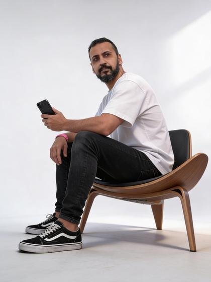Viny Souza sentado, retrato de corpo inteiro em preto e branco